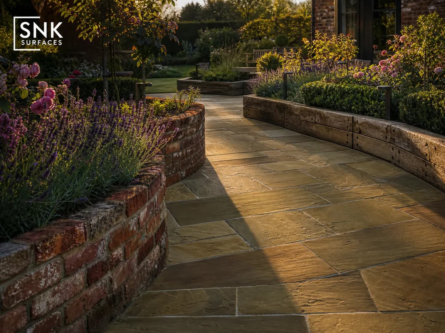 UK garden design combining raj green sandstone paving with red brick retaining walls and aged oak timber sleepers