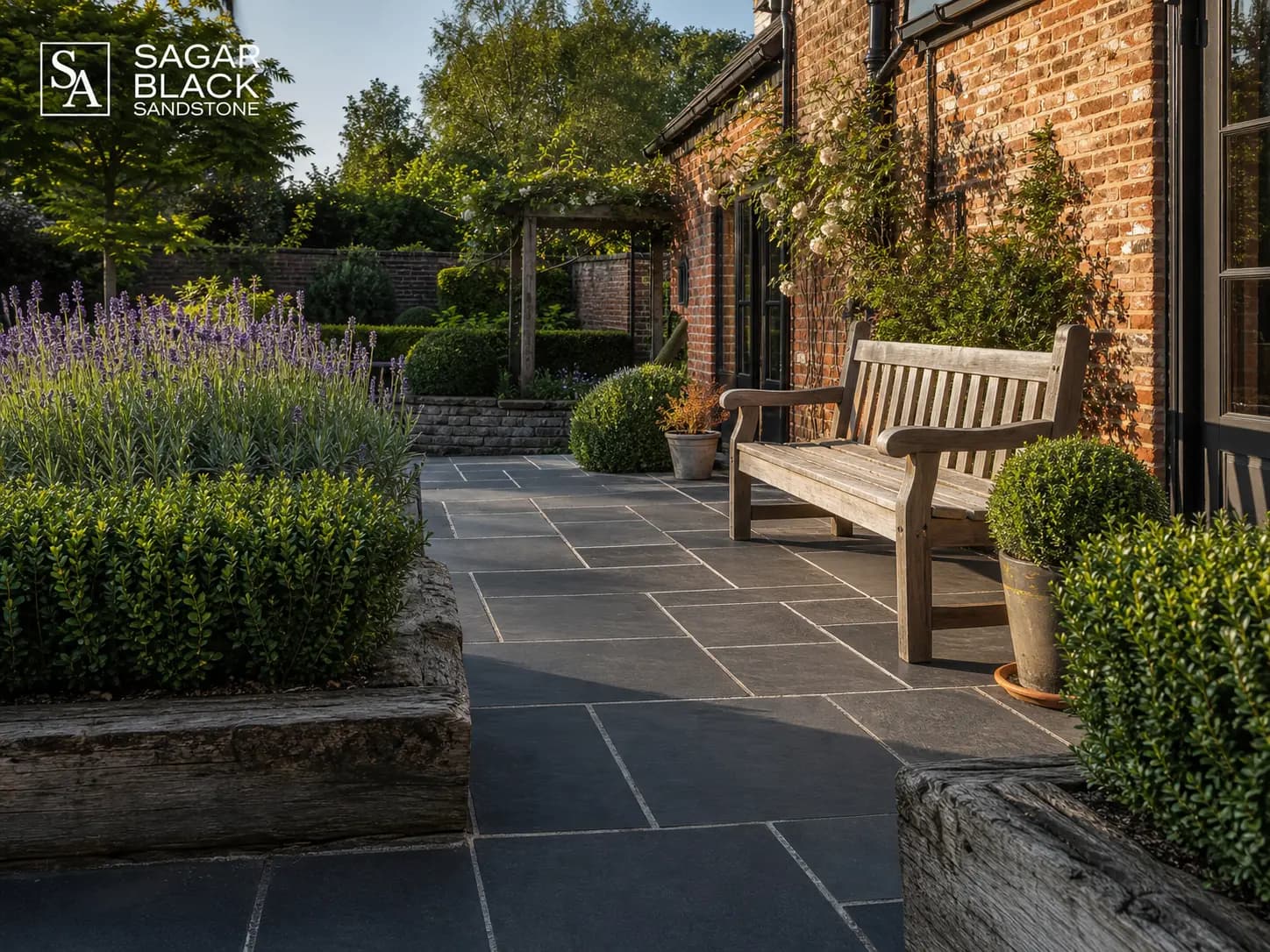 Traditional UK cottage garden with Sagar Black Sandstone mixed-size patio packs and red brick walls