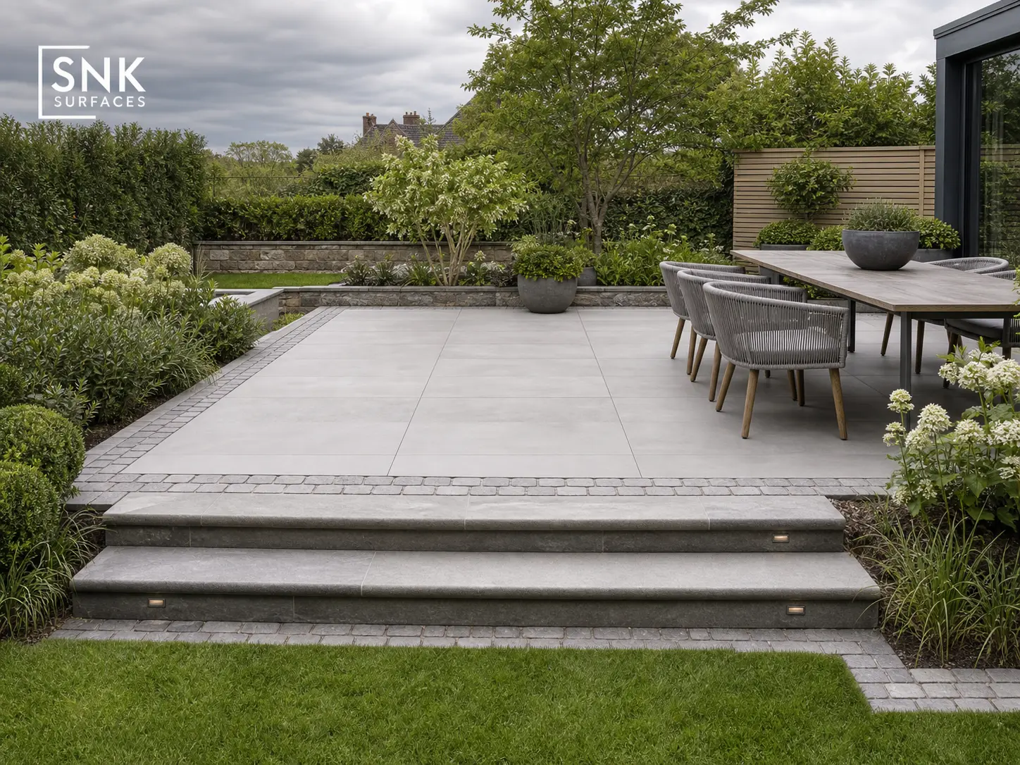 Hybrid UK patio combining Kandla Grey porcelain paving with natural Kandla Grey sandstone setts and steps