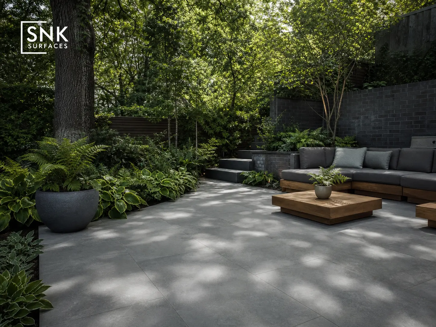Shaded damp UK garden under mature trees paved with pristine Kandla Grey porcelain showing zero algae growth