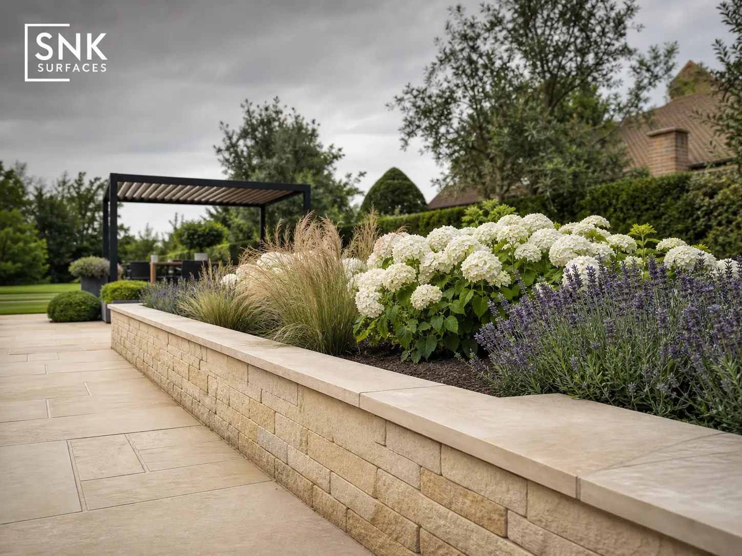 Natural sandstone retaining wall matching sandstone patio paving in a luxury UK garden